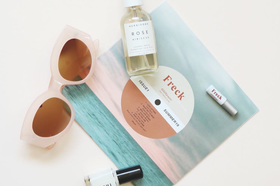 High-angle flatlay of summer essentials including sunglasses and skincare products.